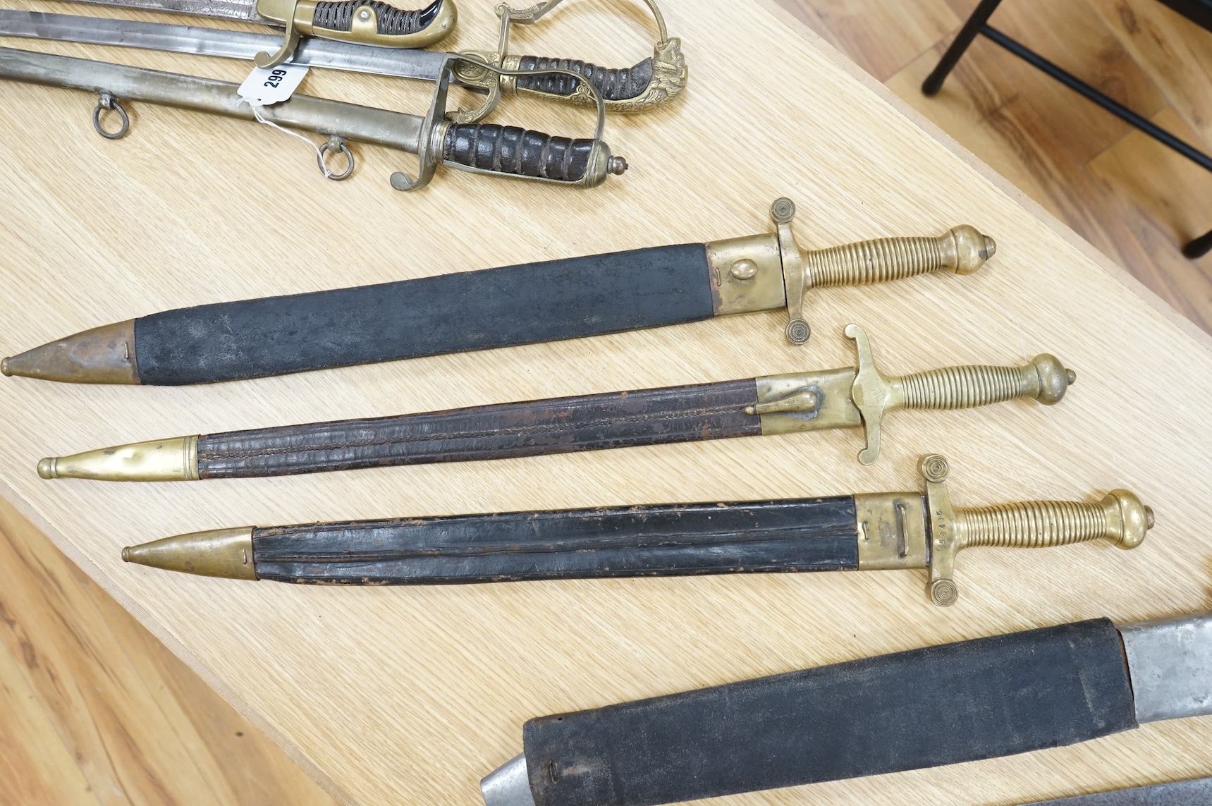 Three Continental infantry officer’s sidearms briquette, the first stamped Paris, in its brass mounted leather scabbard, another similar with sawback blade (illegible stamp), and another similar with thin blade, stamped